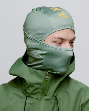 Grøn A.Kjærbede balaclava til ski, orange logo, fra siden på herre